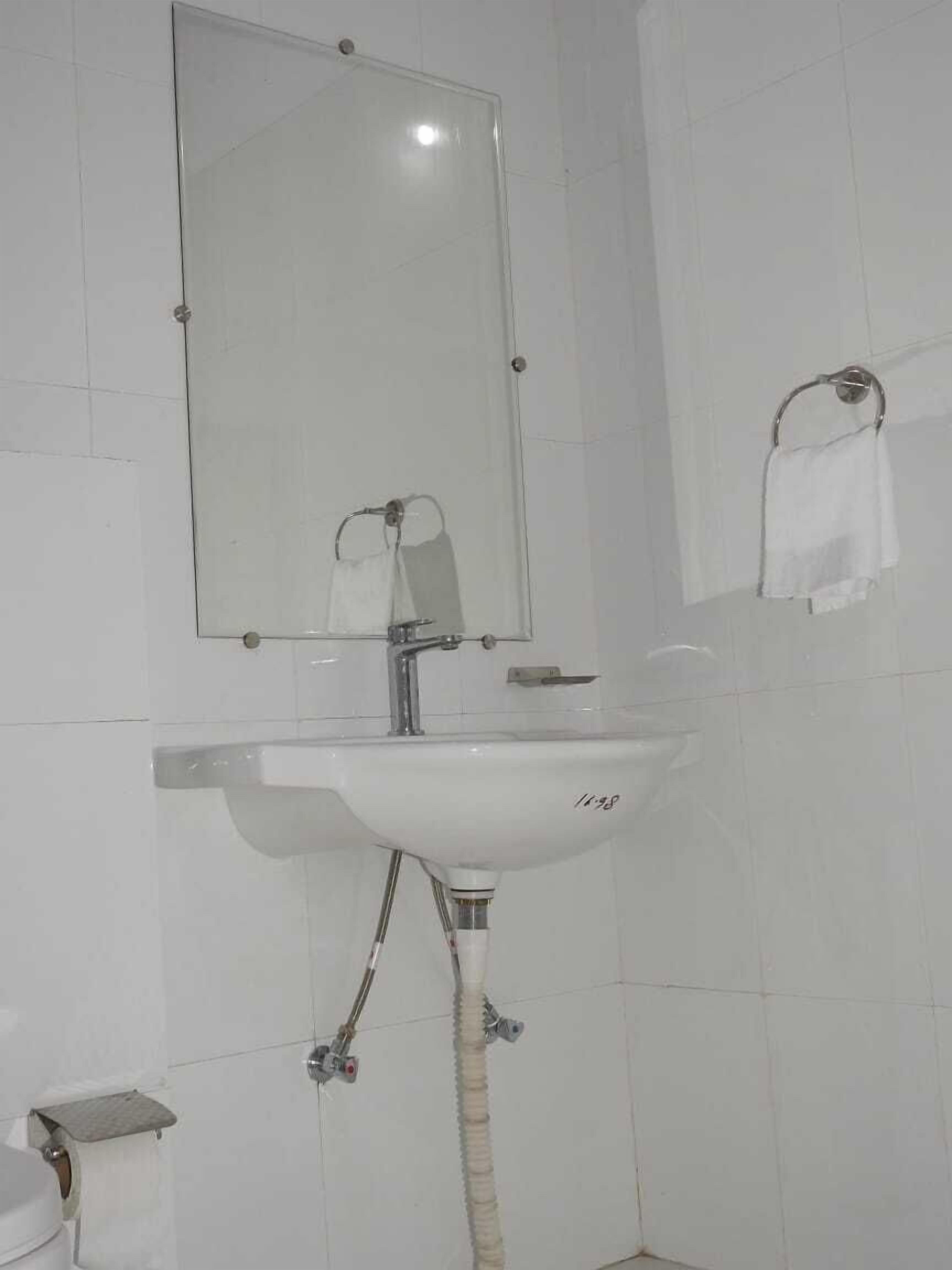 A bathroom with a white sink, a mirror, and a towel rack.