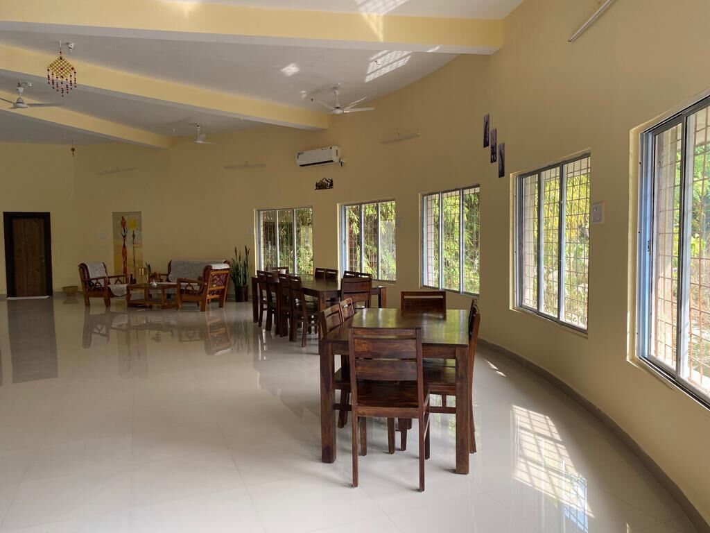 A spacious room with large windows, a ceiling fan, and a polished floor.