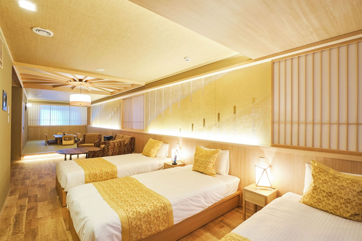 A hotel room with two beds, a desk, and a seating area.
