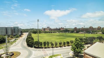 Um campus com um grande campo verde, edifícios e uma estrada com uma rotatória.
