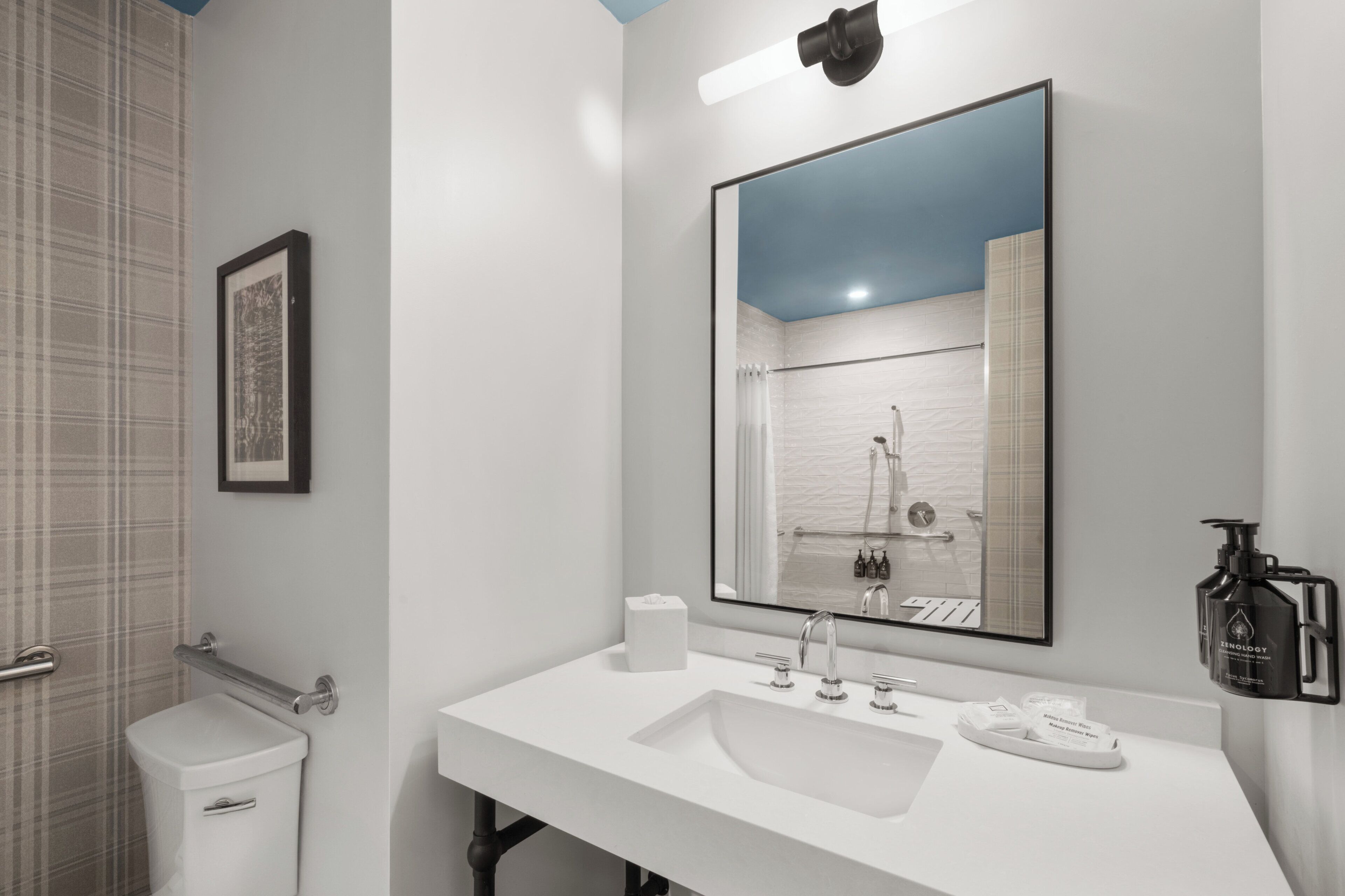 Ein modernes Badezimmer mit Waschbecken, großem Spiegel und Dusche.