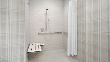 Une douche équipée d’un pommeau de douche à main, d’un flexible de douche et d’une barre d’appui.