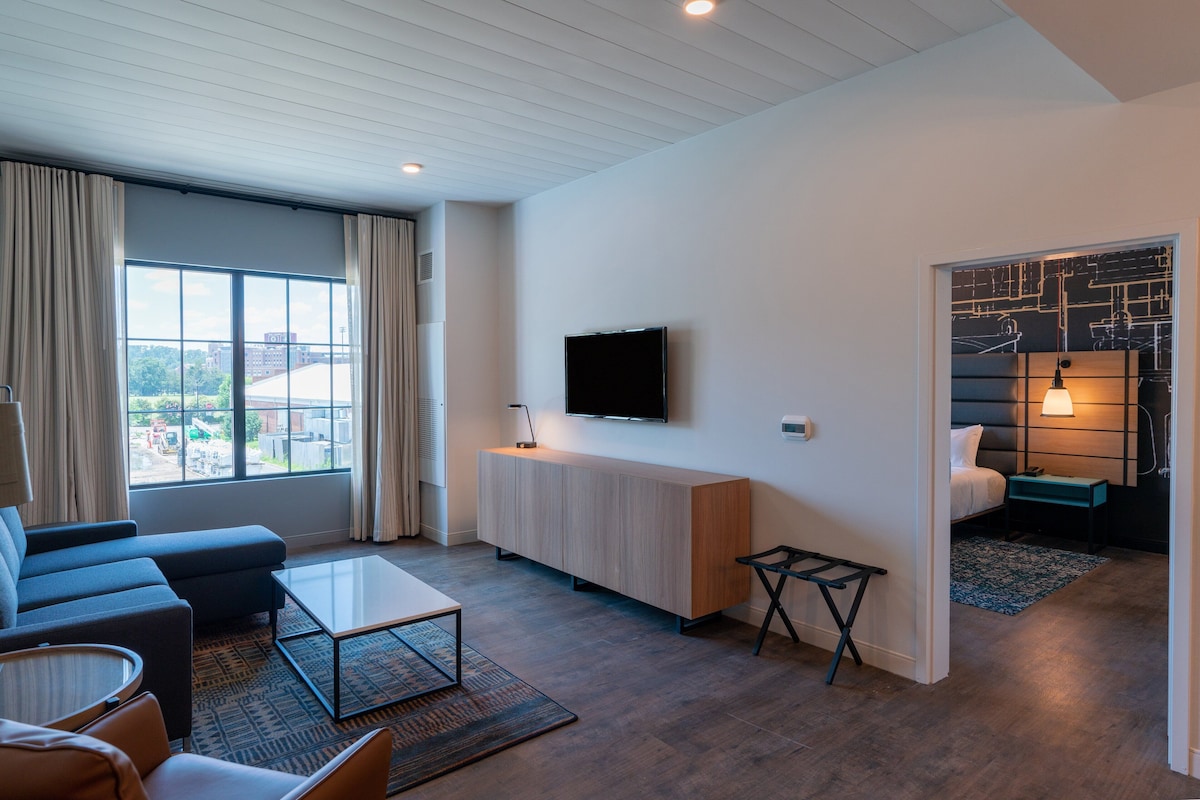 Een moderne woonkamer met een bank, salontafel en een aan de muur bevestigde televisie.