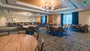 A conference room with multiple tables and chairs, a chandelier, and large windows with curtains. - Hotel Indigo Tallahassee - Collegetown by IHG (Tallahassee)