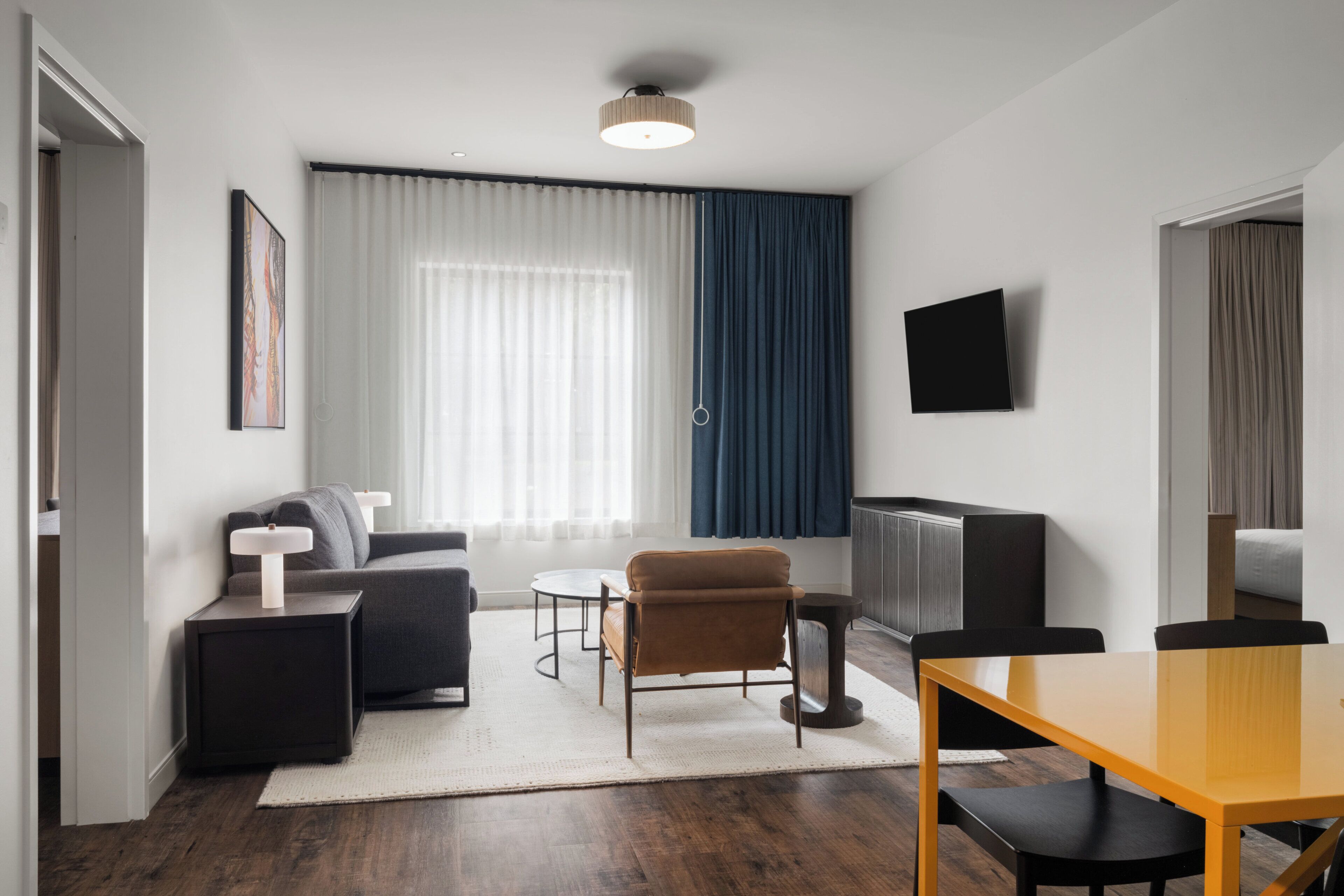 Ein modernes Wohnzimmer mit Sofa, Couchtisch, Esstisch und Fernseher.