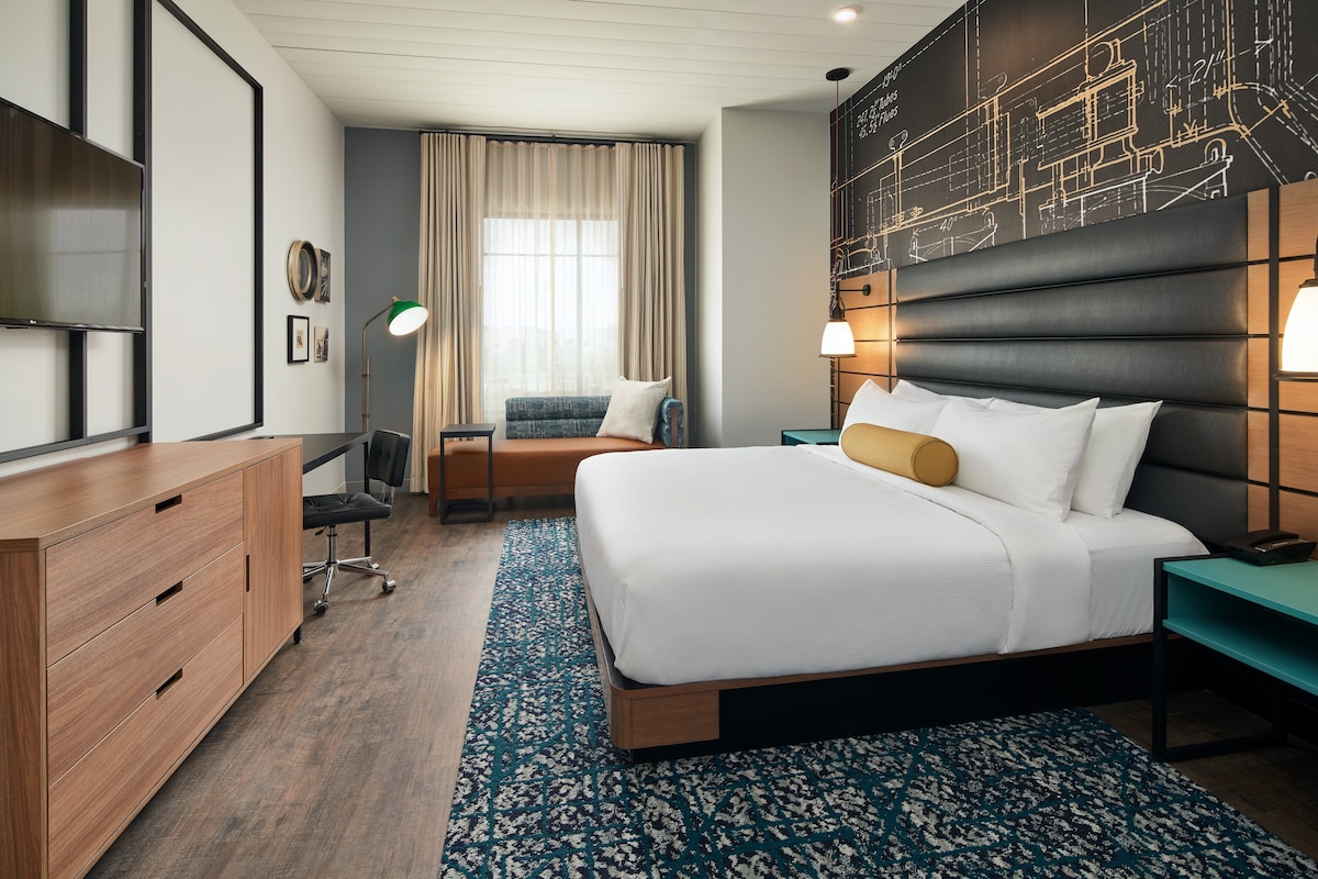 Een moderne hotelkamer met een groot bed, een bureau, een stoel en een televisie.