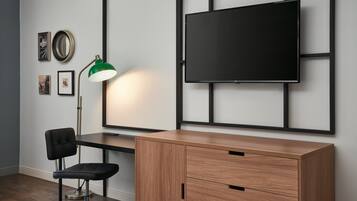 A modern room with a wooden desk, a black office chair, a green desk lamp, and a mounted TV on the wall.