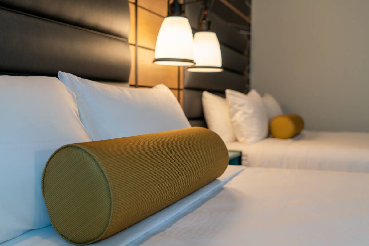 A hotel room with a bed, pillows, and a headboard.
