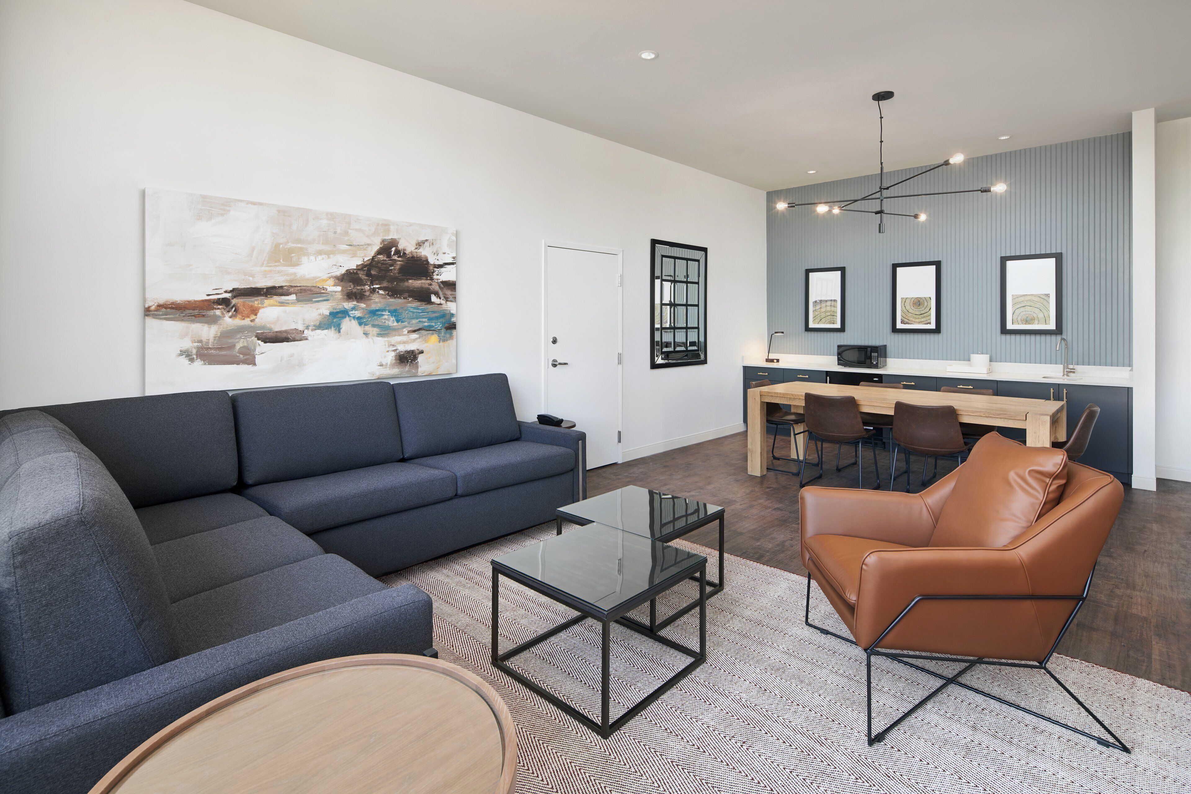 A modern living room with a sectional sofa, a leather armchair, and a glass coffee table.