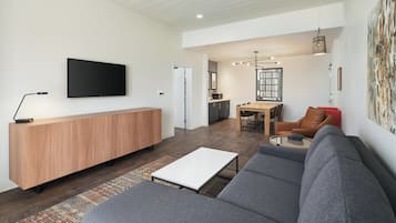 A modern living room with a grey sofa, a wooden coffee table, and a flat-screen TV mounted on the wall.