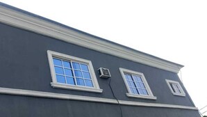 A building with a dark facade, white trim, and two windows with white frames. - Intelligent Hotel and Suites (Port Harcourt)