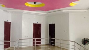 A room with a pink ceiling, white walls, and a metal railing. There are three doors, one of which is red. - Intelligent Hotel and Suites (Port Harcourt)