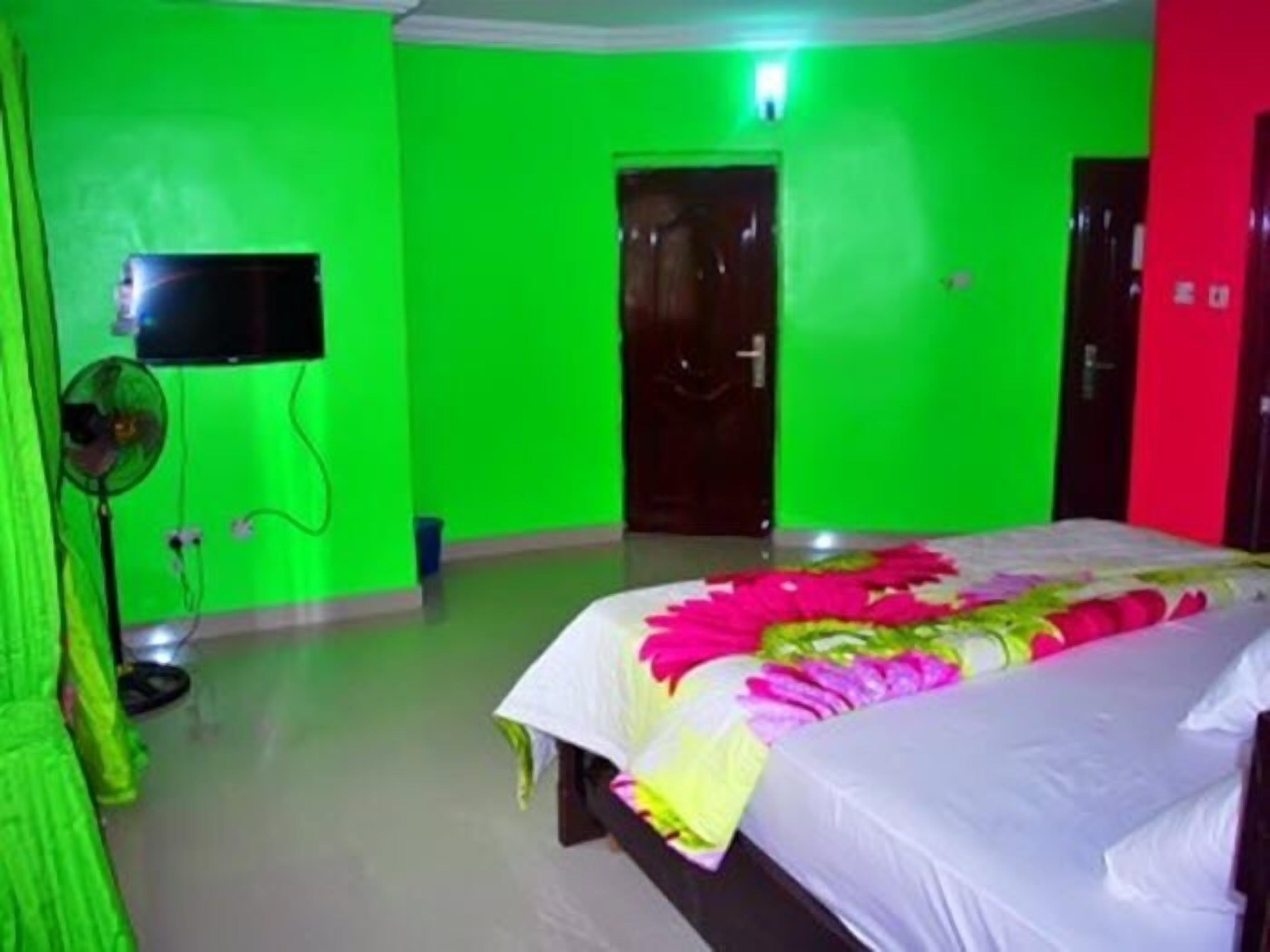 A room with a bed, a television, and a fan.