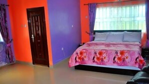 A bedroom with a bed, a door, and a window with curtains. - Intelligent Hotel and Suites (Port Harcourt)