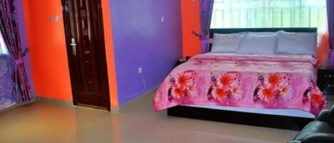 Quarto com uma cama, uma porta e janela com cortinas.
