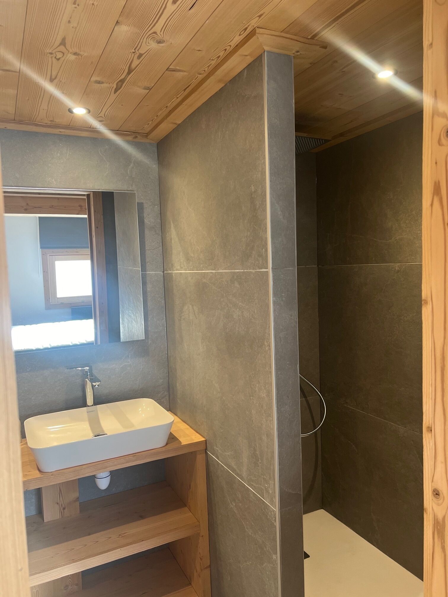 Une salle de bain avec un meuble-lavabo en bois, un lavabo blanc et un miroir.