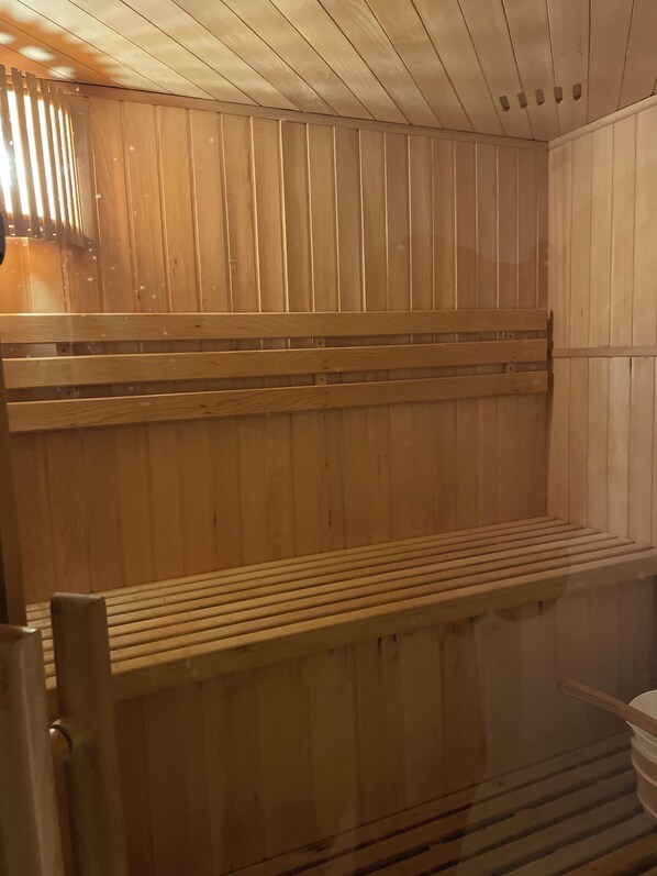 A sauna with wooden benches and a sloped ceiling.