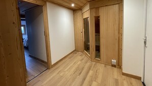 A room with wooden flooring, a white door, and a glass door leading to another room. - New charming chalet, 15 to 16 people with panoramic terrace facing south (Montgenèvre)