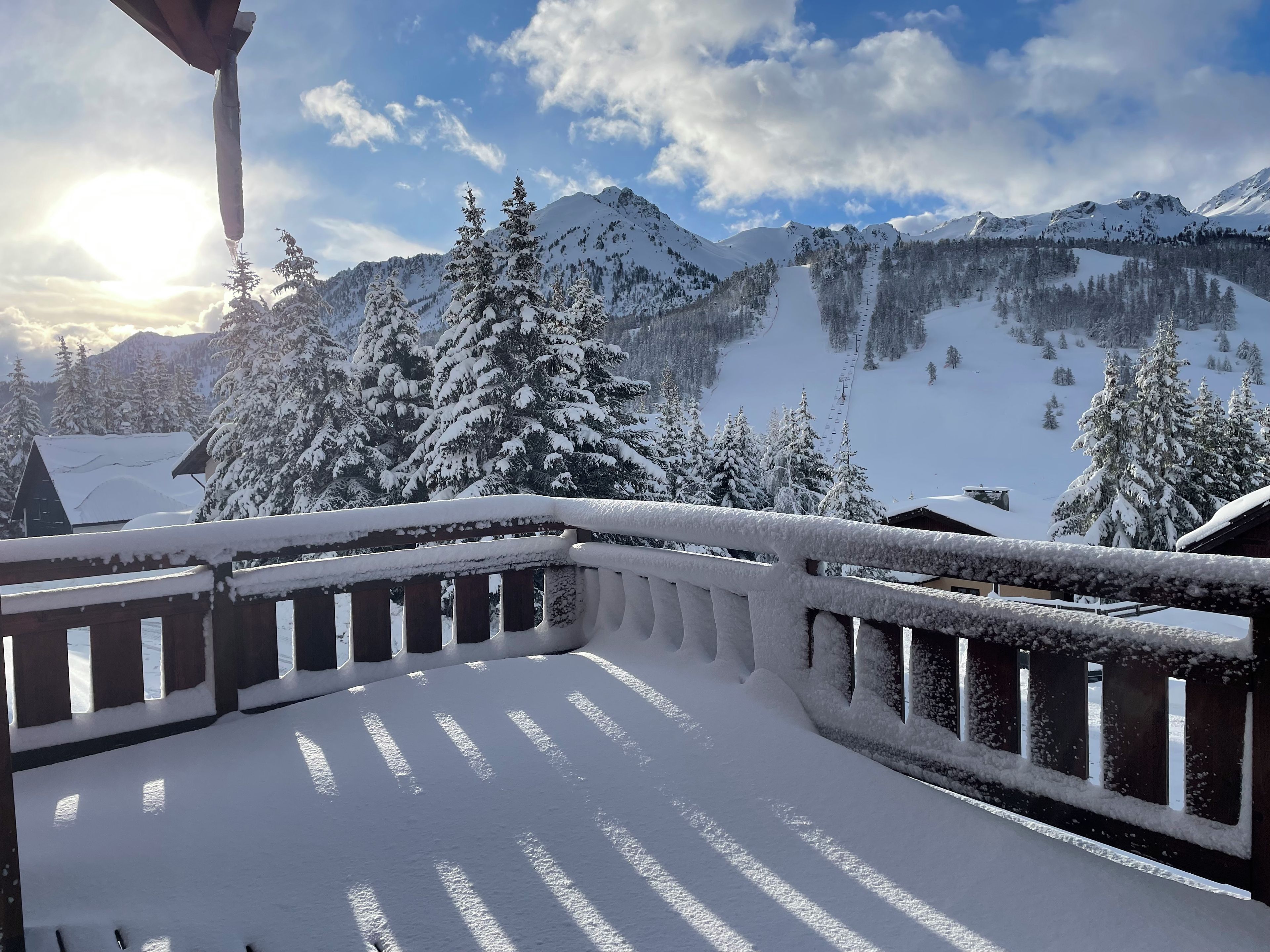A snow-covered balcony with a view of a mountain landscape.