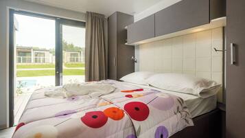A modern bedroom with a bed, a sliding glass door to a balcony, and a view of a pool.