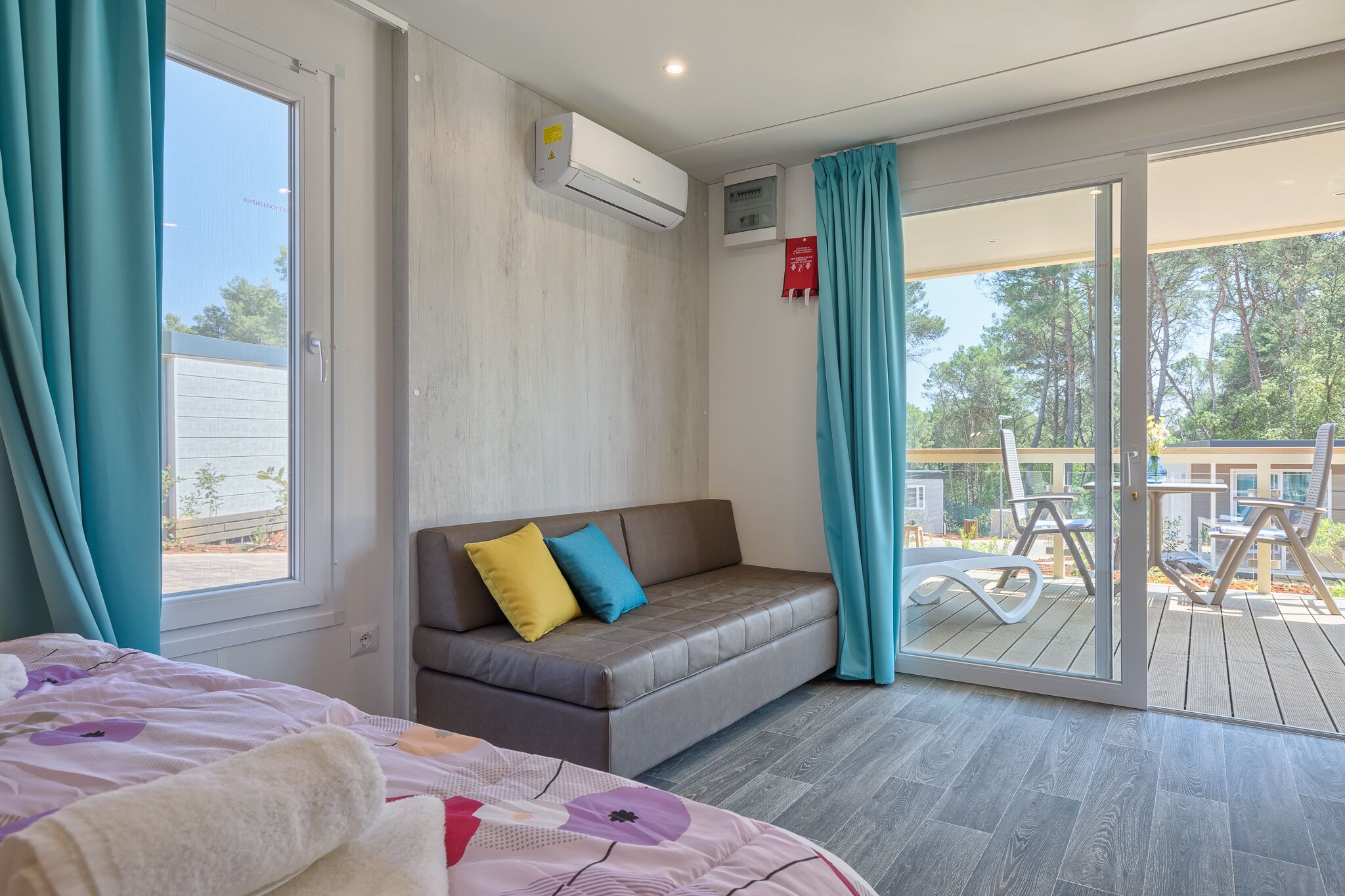 A modern room with a sofa, a bed, and a sliding glass door leading to an outdoor deck.