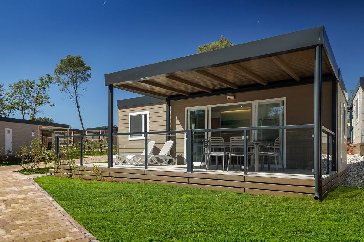 Una casa moderna con un porche cubierto, puertas de cristal y césped.