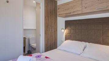 Ein Schlafzimmer mit einem Bett, einem Holzschrank und einem durchgegangenen Tür sichtbaren Badezimmer.