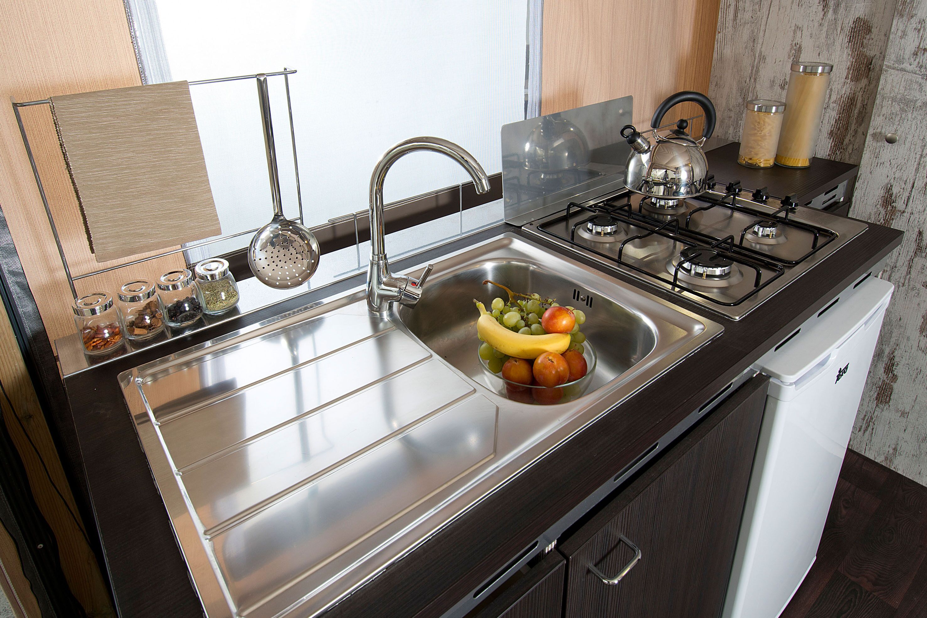 A kitchen with a stainless steel sink, a gas stove, and a white dishwasher.