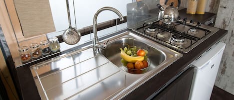 A kitchen with a stainless steel sink, a gas stove, and a white dishwasher.
