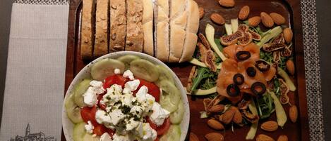 A wooden serving tray with a salad, sliced bread, and almonds.