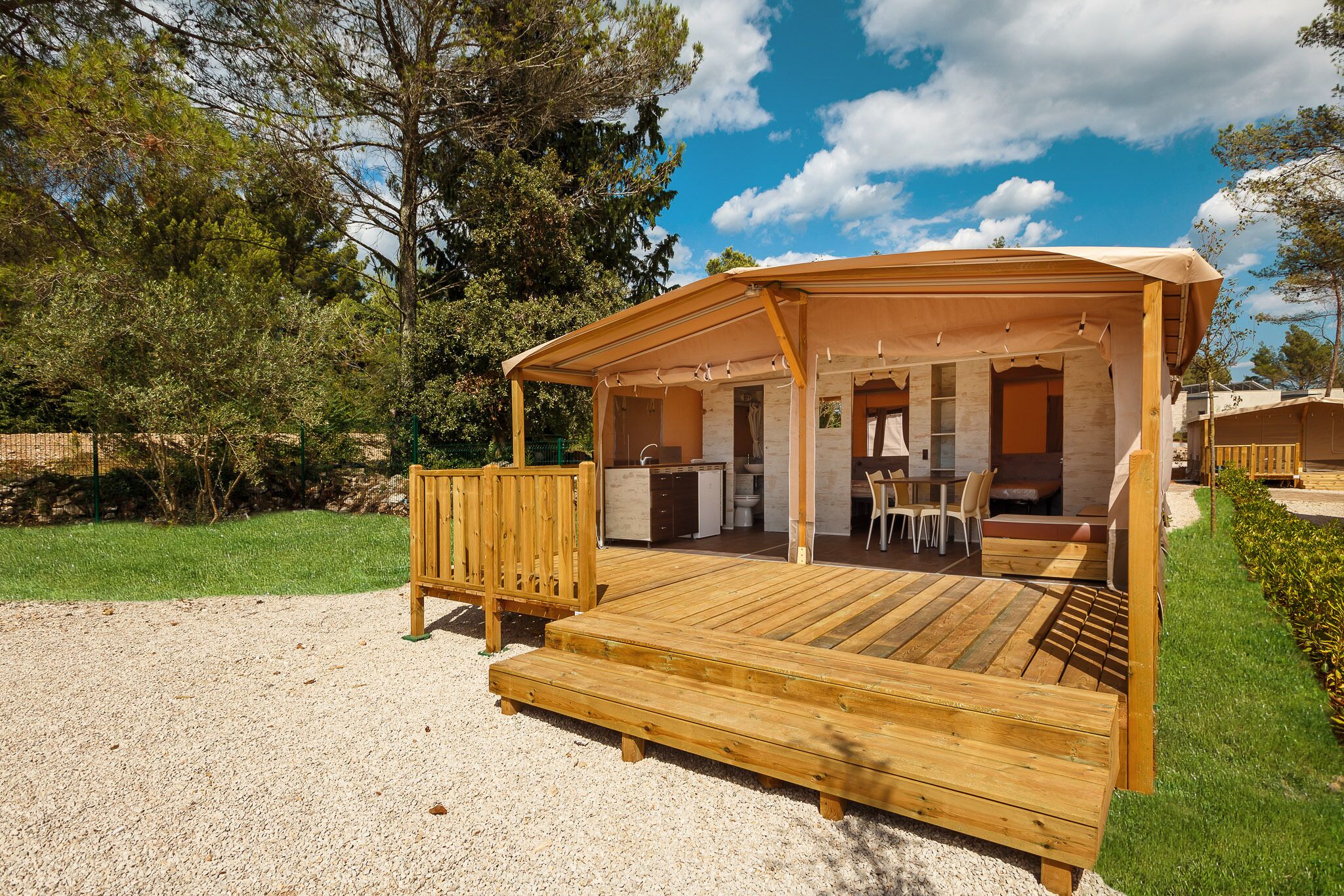 Una terraza de madera con un porche cubierto, una cocina y un comedor.