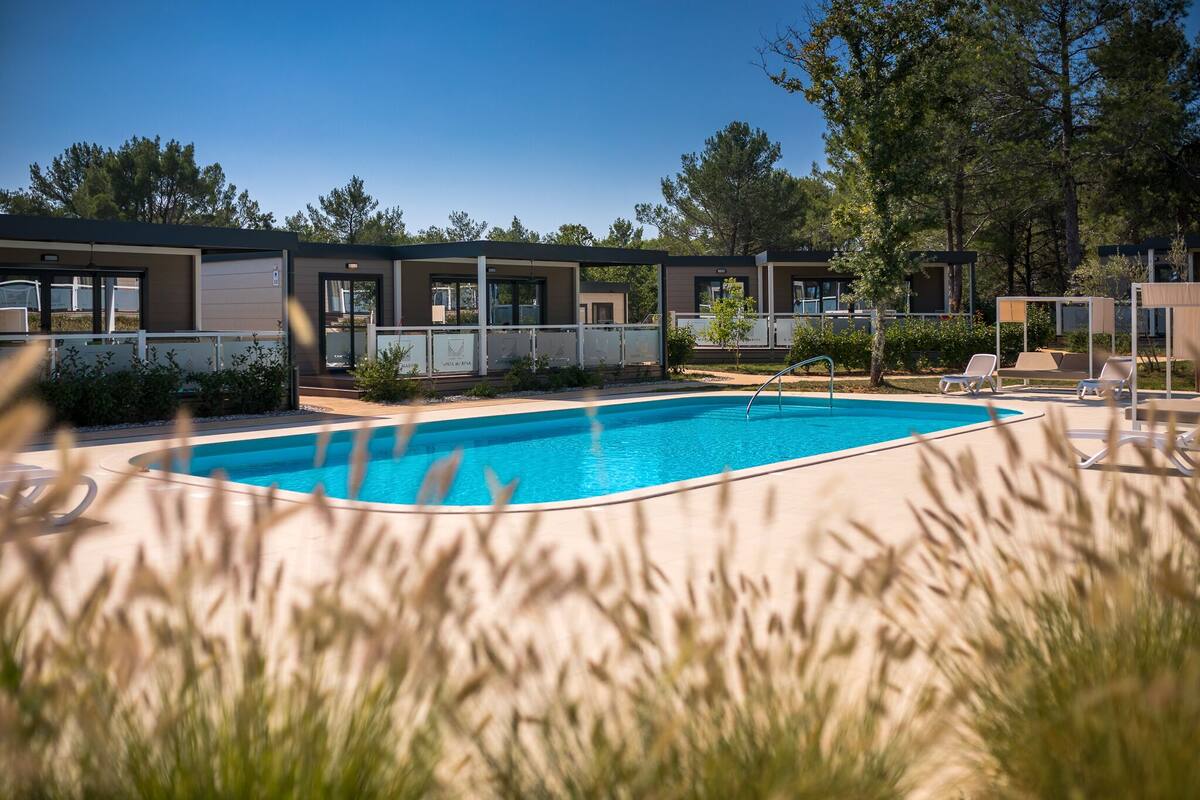 Un área de piscina moderna al aire libre con sillones de descanso y una piscina de color azul cristalino.