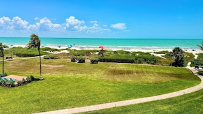 A coastal view with a grassy area, a pathway, and a beach in the background. - Loggerhead Cay #143 - where the view takes your breath away (Sanibel)