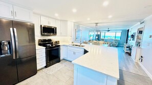 A modern kitchen with a refrigerator, stove, microwave, and a large island.
