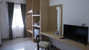Ein modernes Wohnzimmer mit Flachbildfernseher, Holz-TV-Möbel, einem Sessel, einem kleinen Tisch und einer eingebauten Bücherreol.