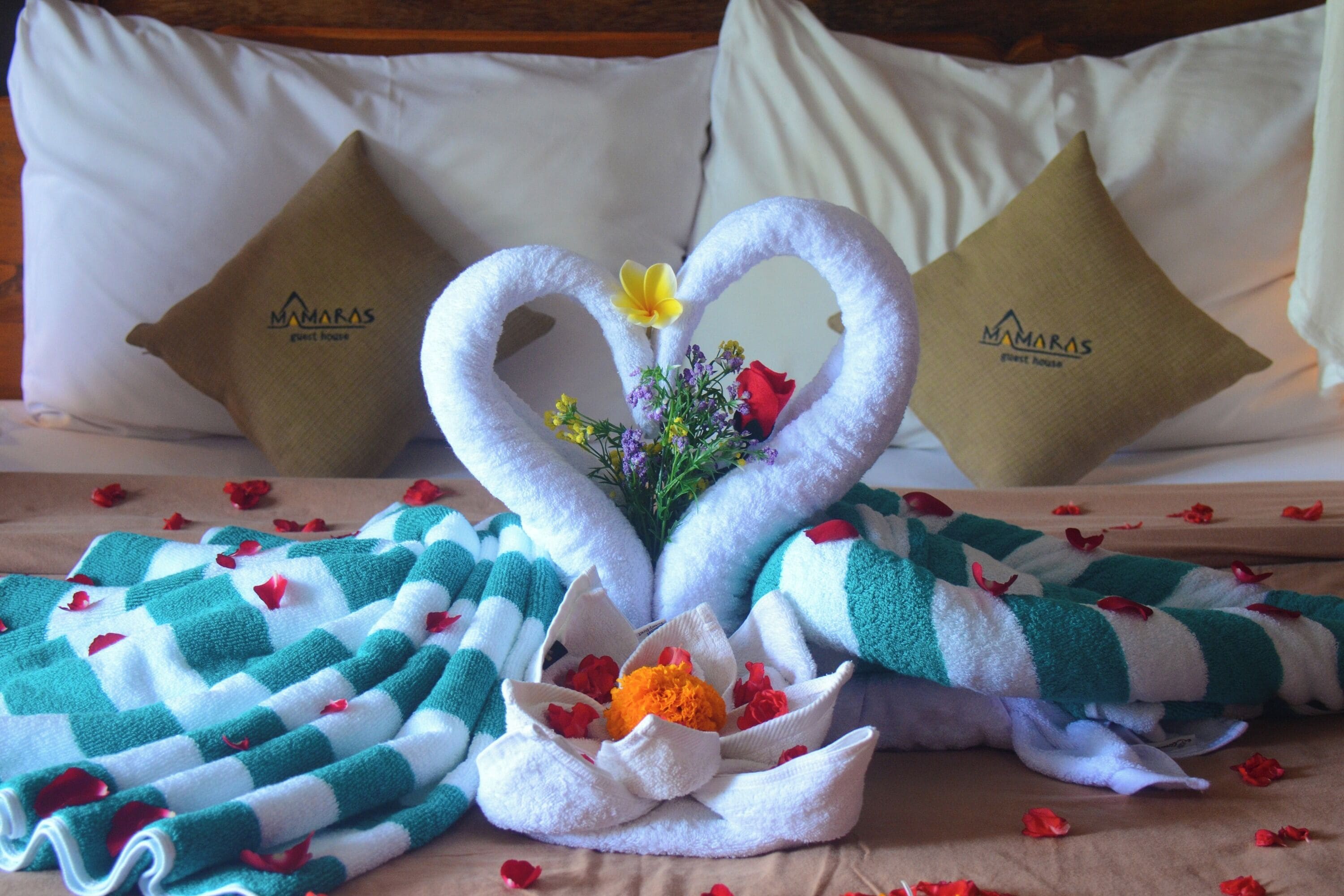 Een bed met een decoratieve opstelling van handdoeken en bloemen.