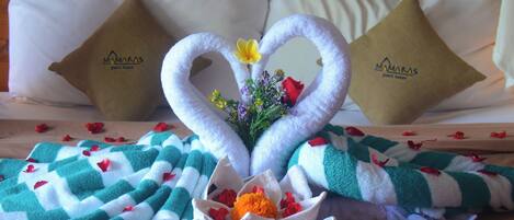 A bed with a decorative arrangement of towels and flowers.