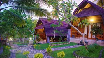 A tropical resort with wooden villas, a stone pathway, and lush greenery.