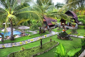 A tropical resort with a swimming pool, palm trees, and a small house with a red roof. - Mamaras Guest House (Penida Island)