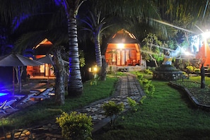 A tropical resort with a thatched-roof building, a stone pathway, and palm trees. - Mamaras Guest House (Penida Island)