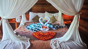 A bed with a heart-shaped flower arrangement, two swan-shaped pillows, and a wooden headboard. - Mamaras Guest House (Penida Island)
