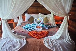 A bed with a heart-shaped flower arrangement, two swan-shaped pillows, and a wooden headboard. - Mamaras Guest House (Penida Island)
