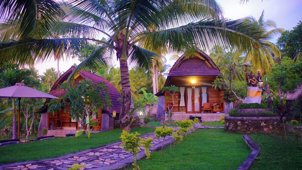 A tropical resort with wooden cottages, a stone pathway, and lush greenery. - Mamaras Guest House (Penida Island)