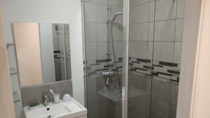 Un bagno moderno con doccia vetrata, lavabo bianco e specchio.