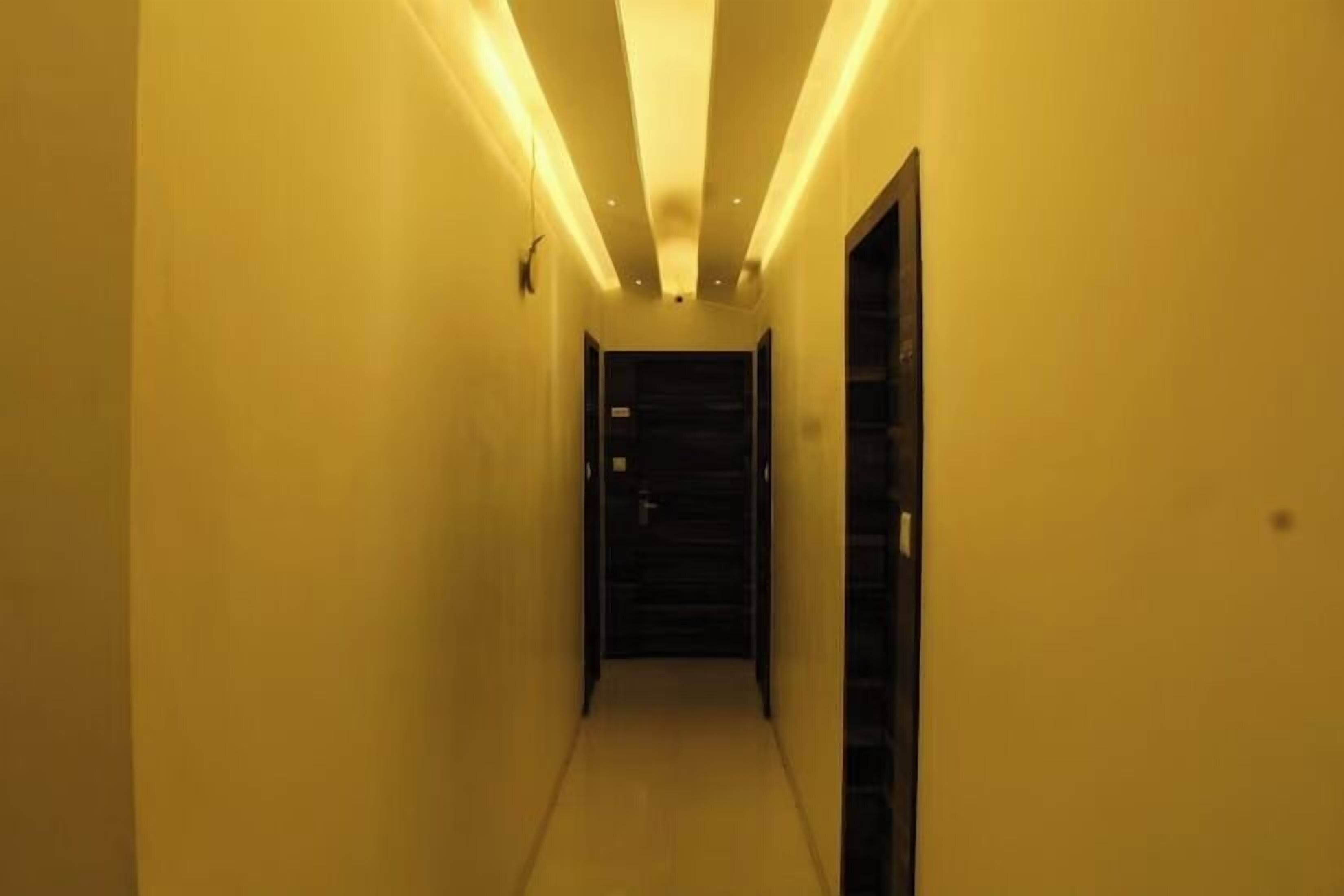 A narrow hallway with a door at the end, illuminated by overhead lights.