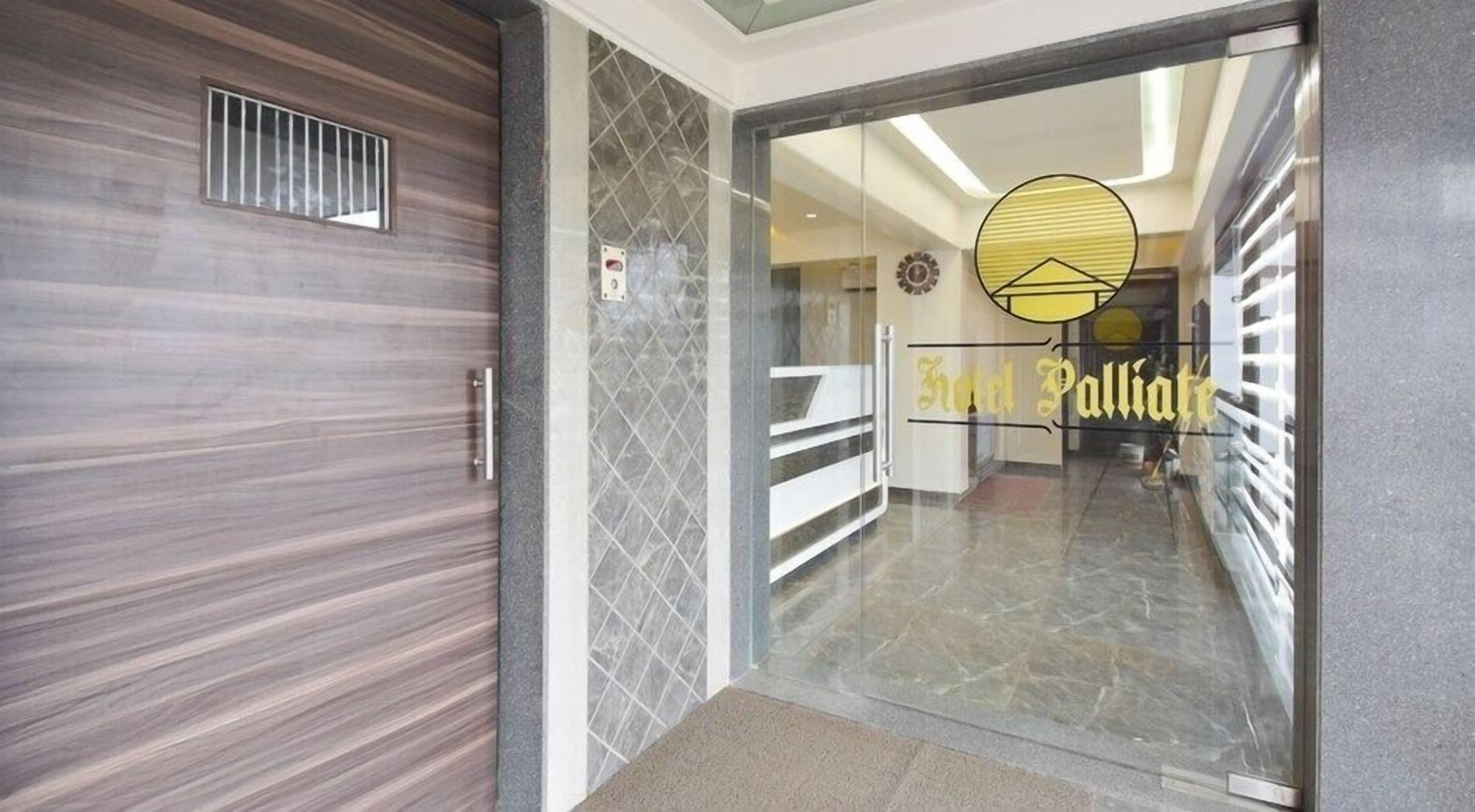 A hotel entrance with a modern design, a glass door, and a visible interior hallway.