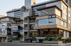 A multi-story hotel with a prominent staircase, a sign for 'Hotel Palliate,' and a 'Sharda' sign indicating a nearby establishment. - Hotel Palliate (Ahmedabad)