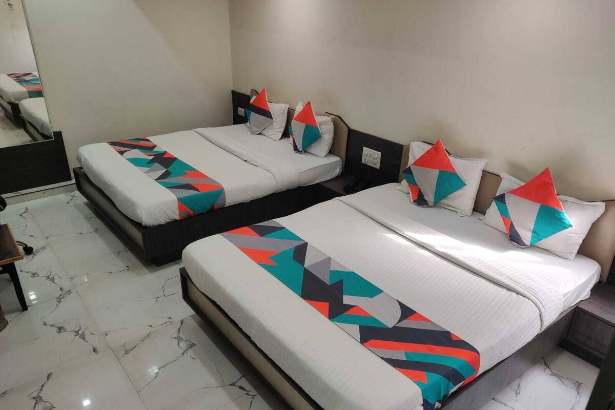Two beds with geometric-patterned bedding, a marble floor, and a mirror on the wall.