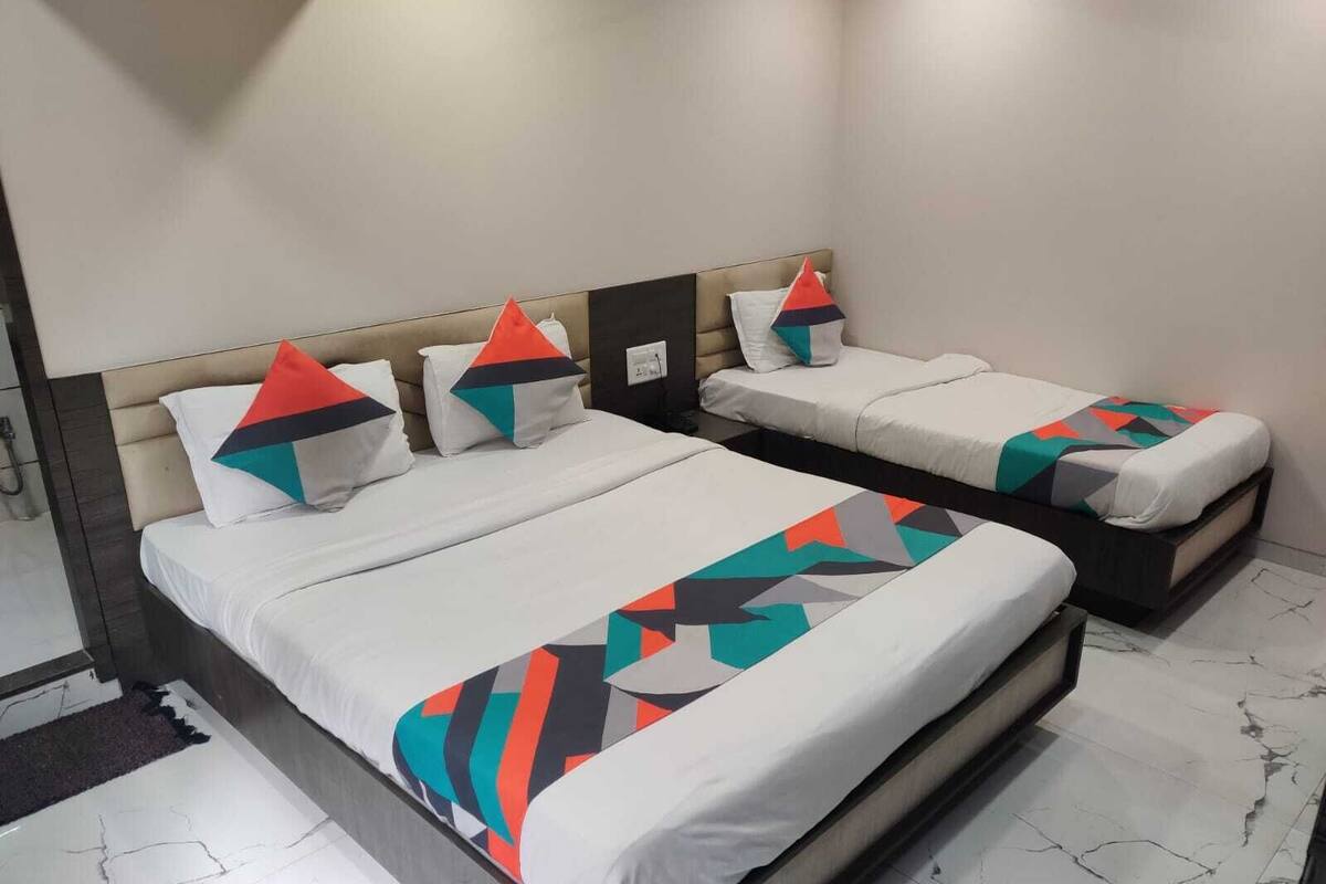 A hotel room with two beds, each with a geometric-patterned bedspread, a headboard, and pillows.