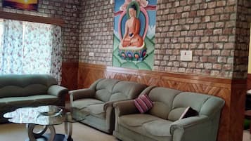 A room with a brick wall, a green sofa, a wooden bench, and a glass table.